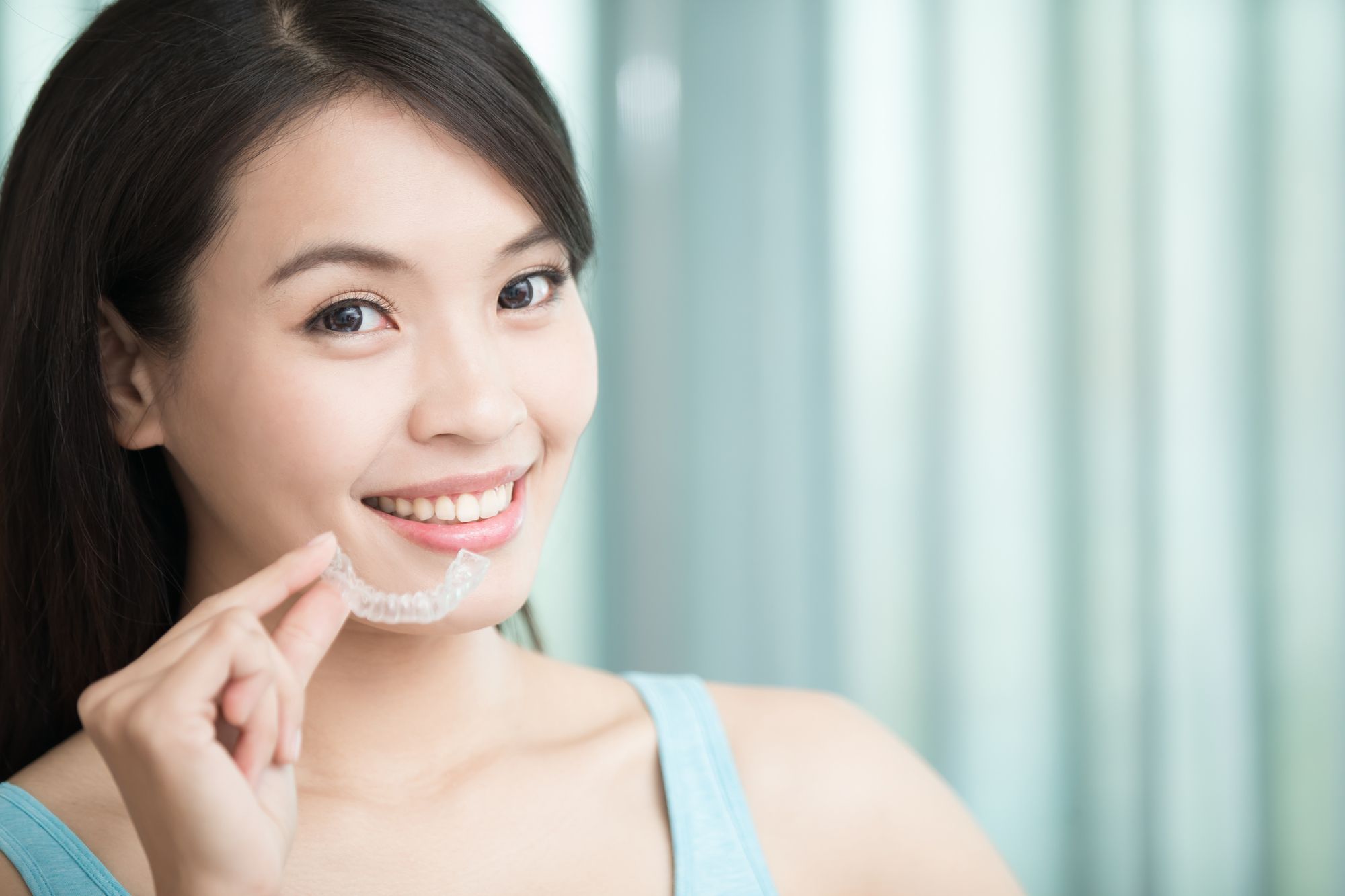 woman smiling holding her ClearCorrect invisible braces