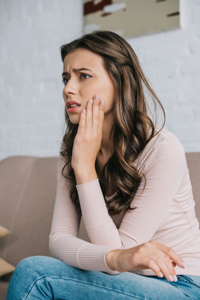 patient holding her tooth in pain