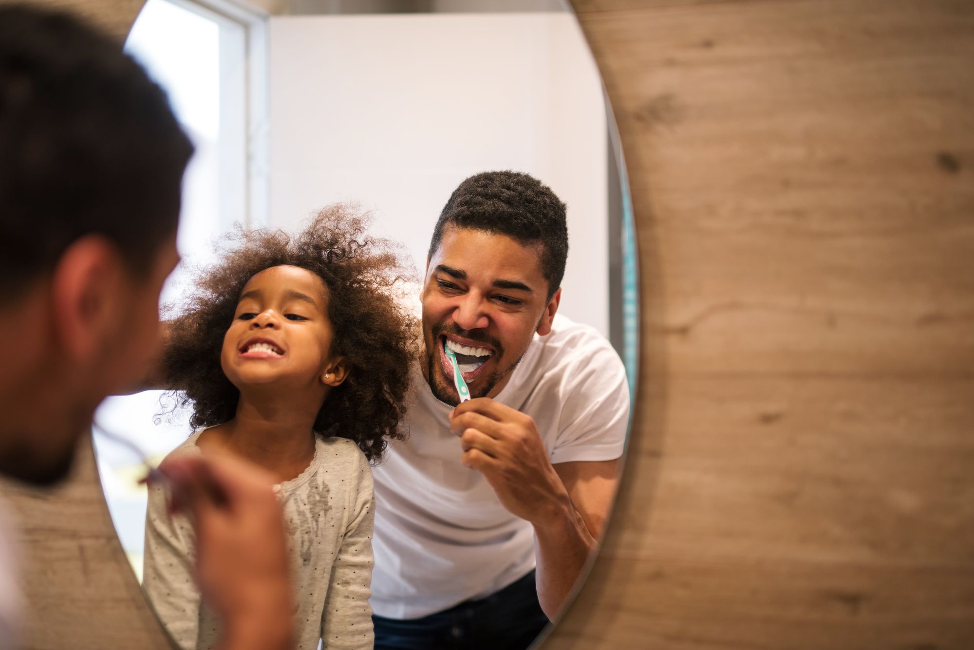 father and daughter brushing their teeth together